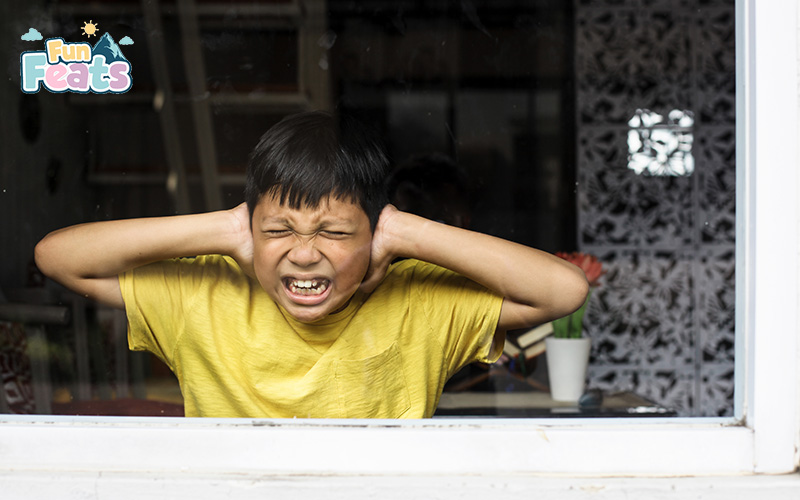 Child covering ears and showing discomfort, highlighting sensitivity to sensory triggers.